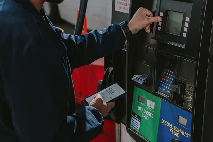 Driver using Uber Freight carrier card and looking at the carrier app at the fuel pump